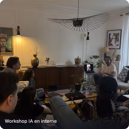 Group of people attending an indoor workshop with a presenter speaking near a laptop in a cozy living room setting.