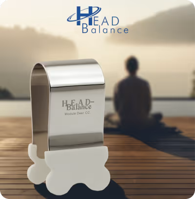 Dispositif argenté Head Balance sur un pont en bois avec une personne assise en méditation devant un paysage brumeux.