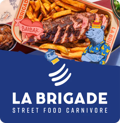 Assiette de frites avec steak tranché et un petit bol d'accompagnement au coin, avec illustration d'un ours tatoué portant une chemise fleurie et une couronne, et texte La Brigade Street Food Carnivore.
