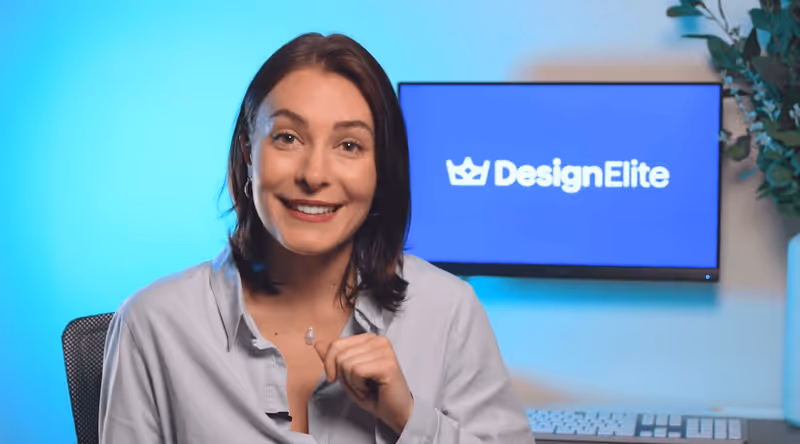 Femme souriante avec une chemise grise posant devant un écran affichant le logo DesignElite.